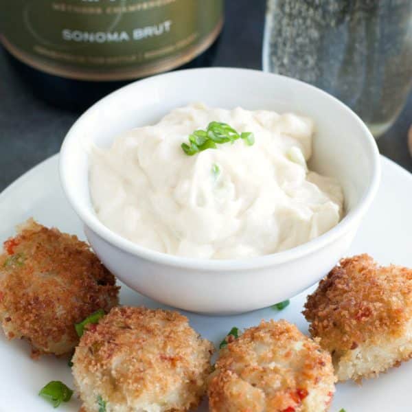 Plate with crab cakes and bowl of white sauce.