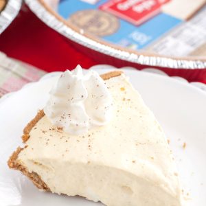 Piece of creamy pie on plate with graham cracker crust.