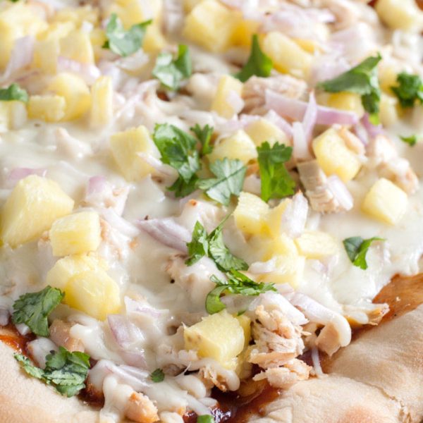 Pizza on baking dish with chicken, cheese and pineapple.