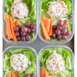Container with chicken salad, carrots and grapes.