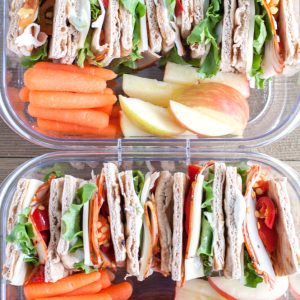 Container with stacked sandwich carrot stacks and apple slices.