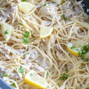 Slow cooker with pasta and lemon wedges.