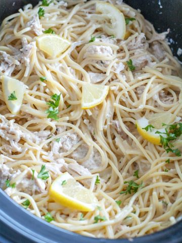 Slow cooker with pasta and lemon wedges.