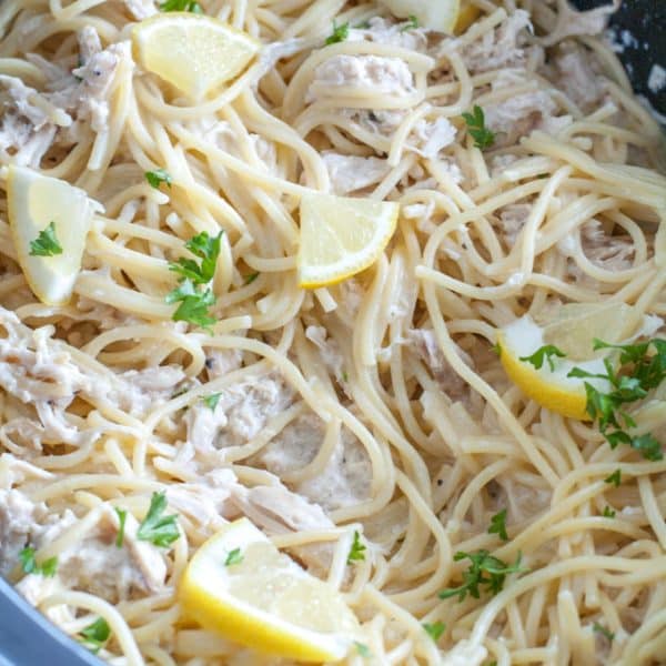 Slow cooker with pasta and lemon wedges.