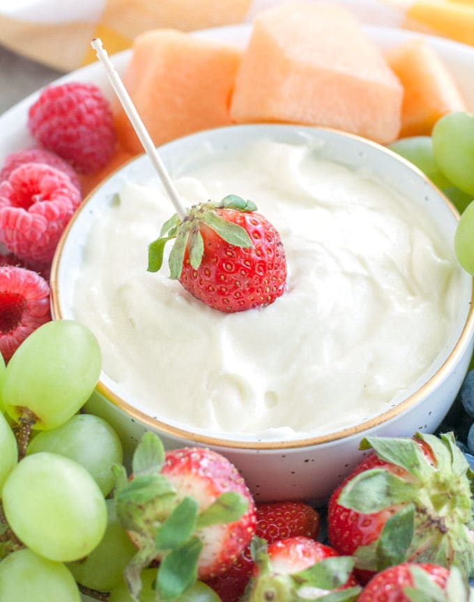 Cream cheese fruit dip in a bowl with a strawberry and toothpick