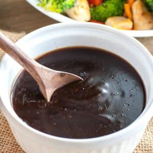 Bowl of teriyaki sauce and plate of vegetables.