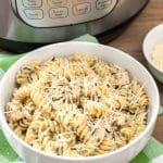 Cooked pasta and chicken in a bowl sitting beside Instant Pot.