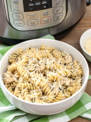 Cooked pasta and chicken in a bowl sitting beside Instant Pot.