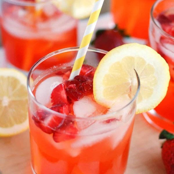 Glass with strawberry lemonade and yellow straw.