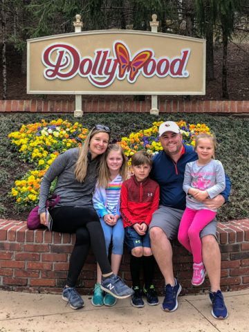 Family sitting in front of Dollywood sign.