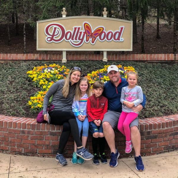 Family sitting in front of Dollywood sign.