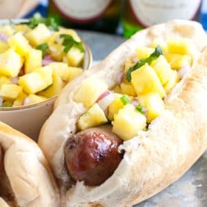 Sausage in hot dog bun topped with pineapple salsa.