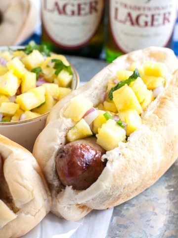 Sausage in hot dog bun topped with pineapple salsa.