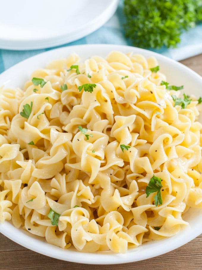 Buttered Noodles with parsley in a white bowl 