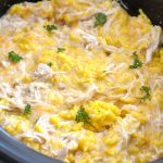 Slow cooker with shredded chicken, yellow rice and shredded cheese.