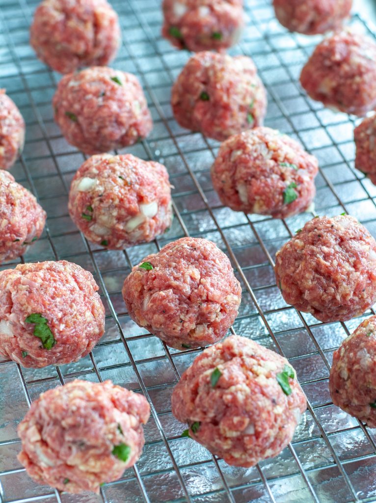 Rolled meatballs on a wire rack ready to be baked