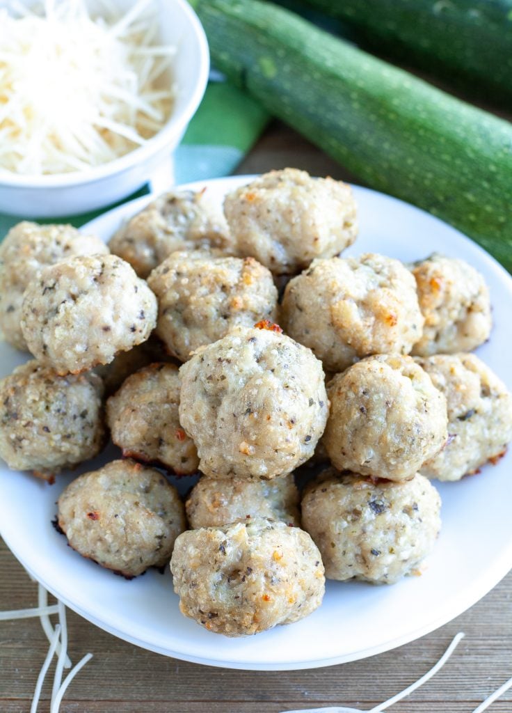 Parmesan Pesto meatballs stacked on a plate with parmesan cheese