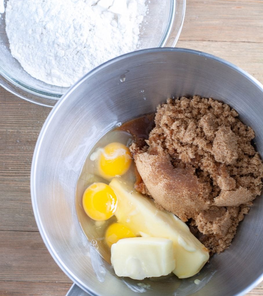 Mixing bowl of brown sugar, eggs, butter and bowl of flour for brownies.