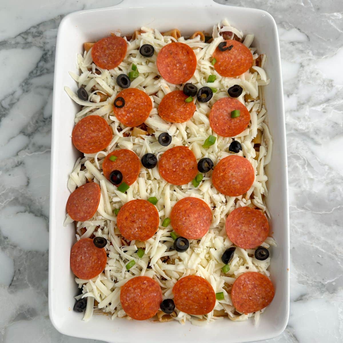 Casserole dish with uncooked pizza casserole. 