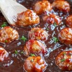 Meatballs in sauce with wooden spoon.