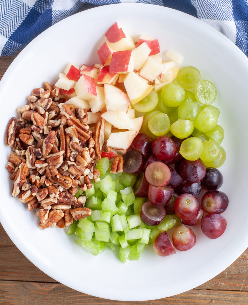 Bowl of ingredients, apples, pecans, grapes, celery.