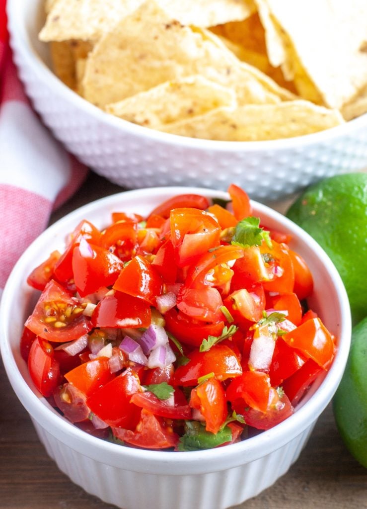 Small bowl of pico de gallo with a bowl of tortilla chips