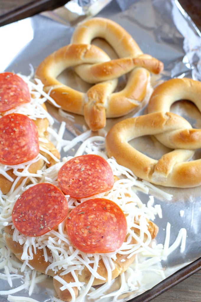 Soft pretzels on foil with pepperoni and cheese. 