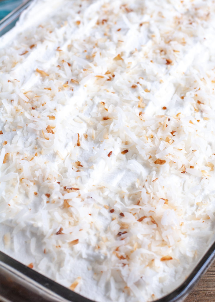 Orange Poke Cake Topped with whipped topping and toasted coconut