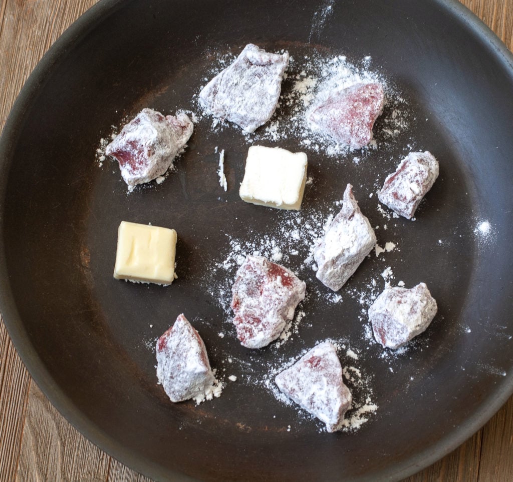 Beef dredged in flour in a pan with butter