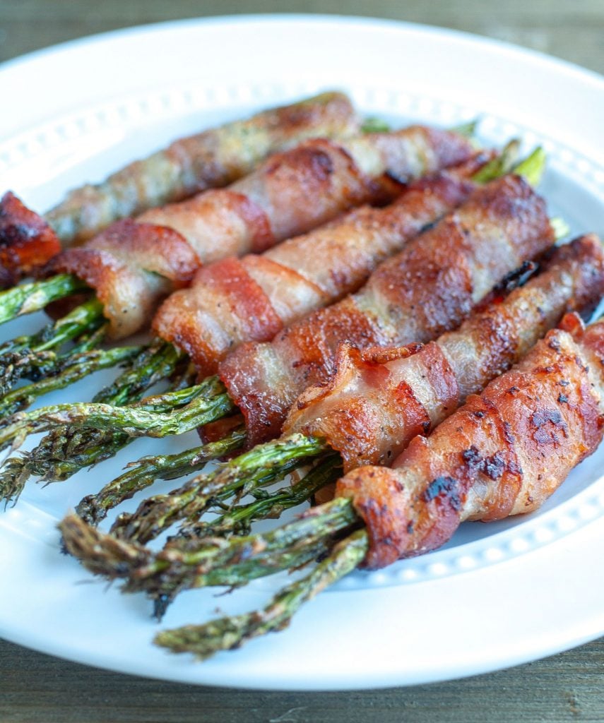 Asparagus wrapped in bacon that was cooked in the Air Fryer on a white plate