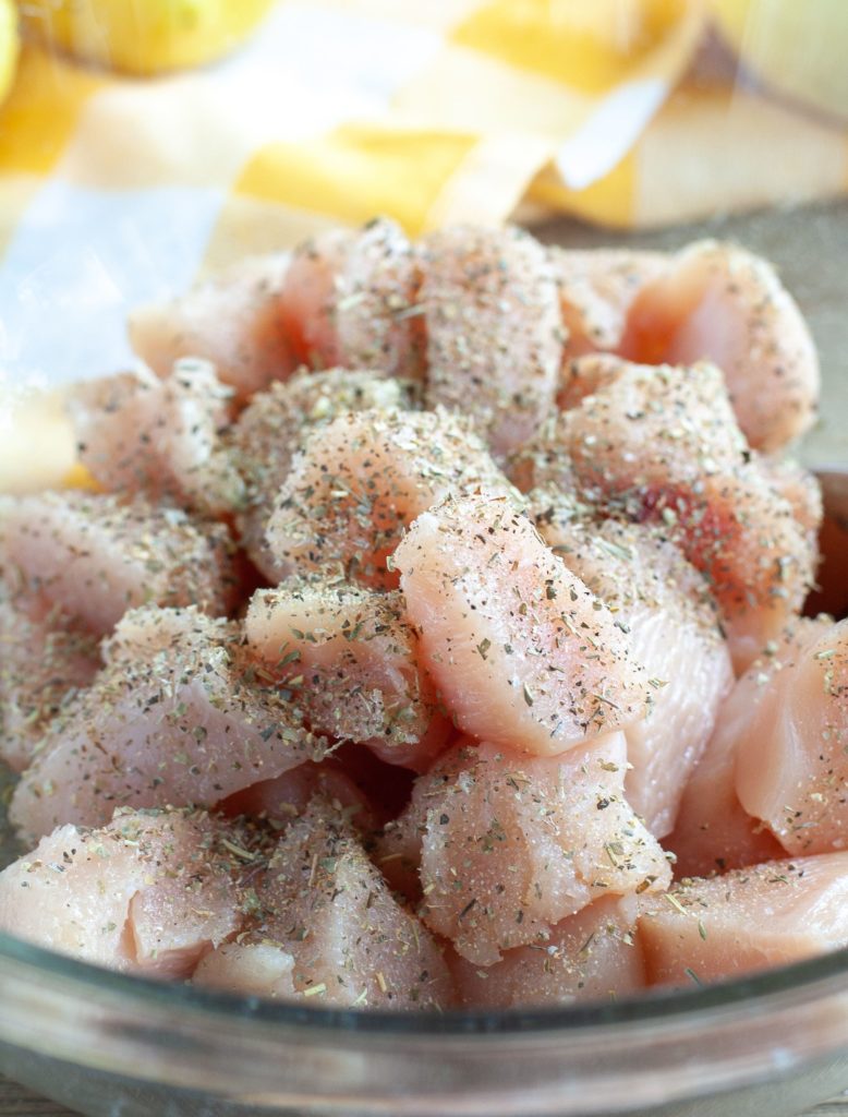 Diced chicken with seasoning in a glass bowl