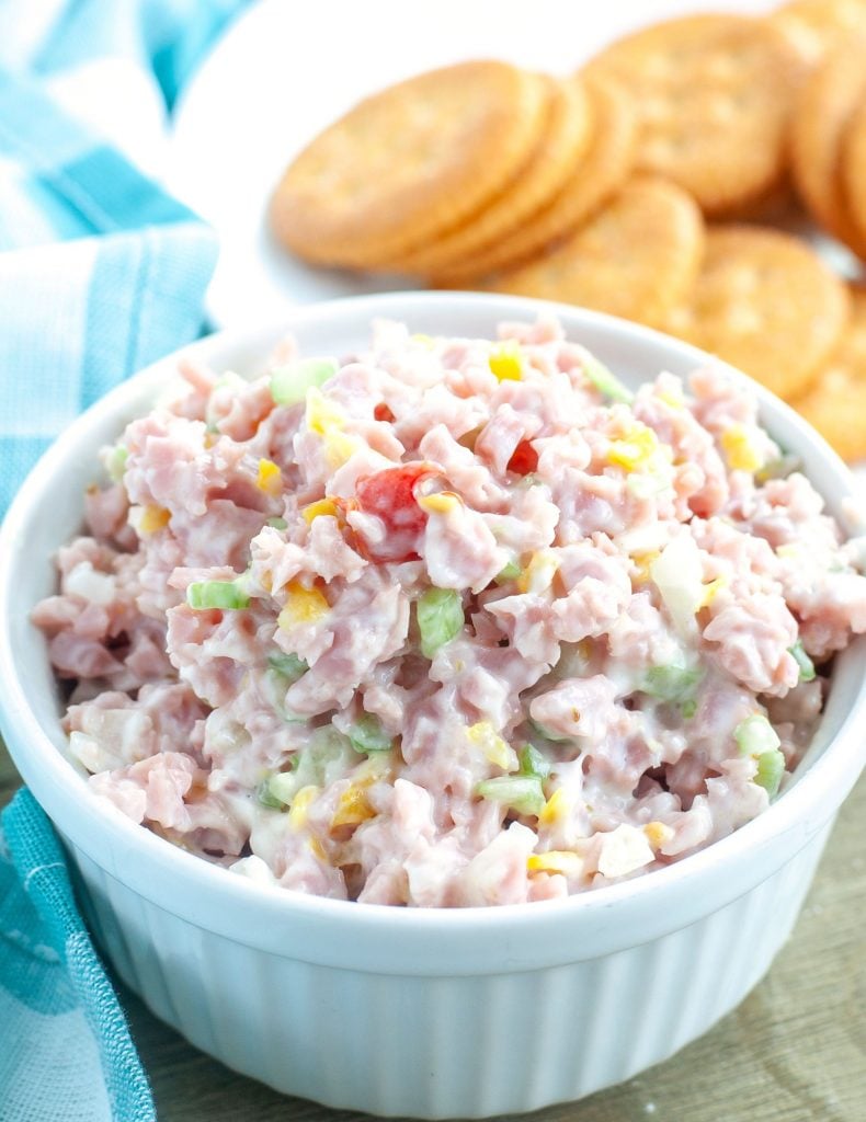 Ham salad in a white bowl with crackers in the background