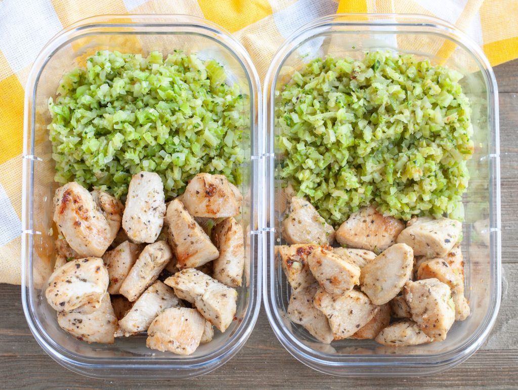 2 meal prep containers with garlic chicken and riced veggies