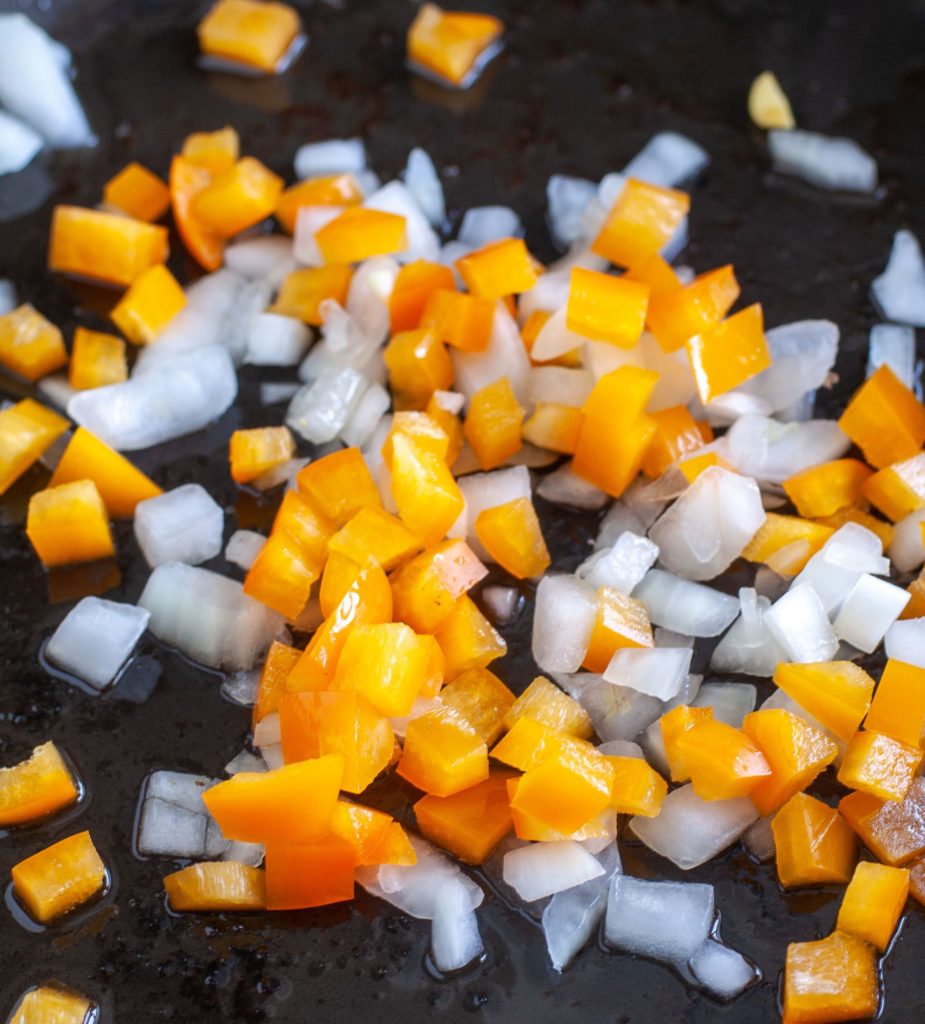 Diced onion and orange bell pepper in a skillet