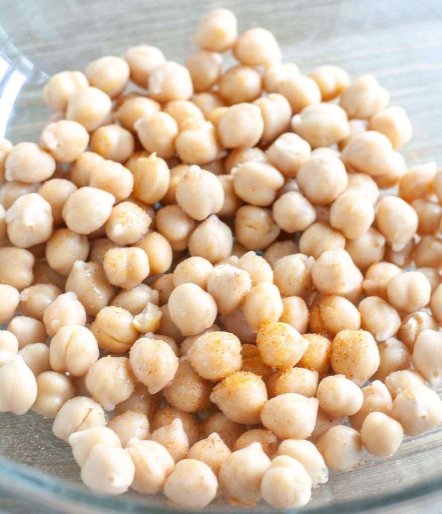 Chickpeas in a glass bowl with olive oil and seasoning