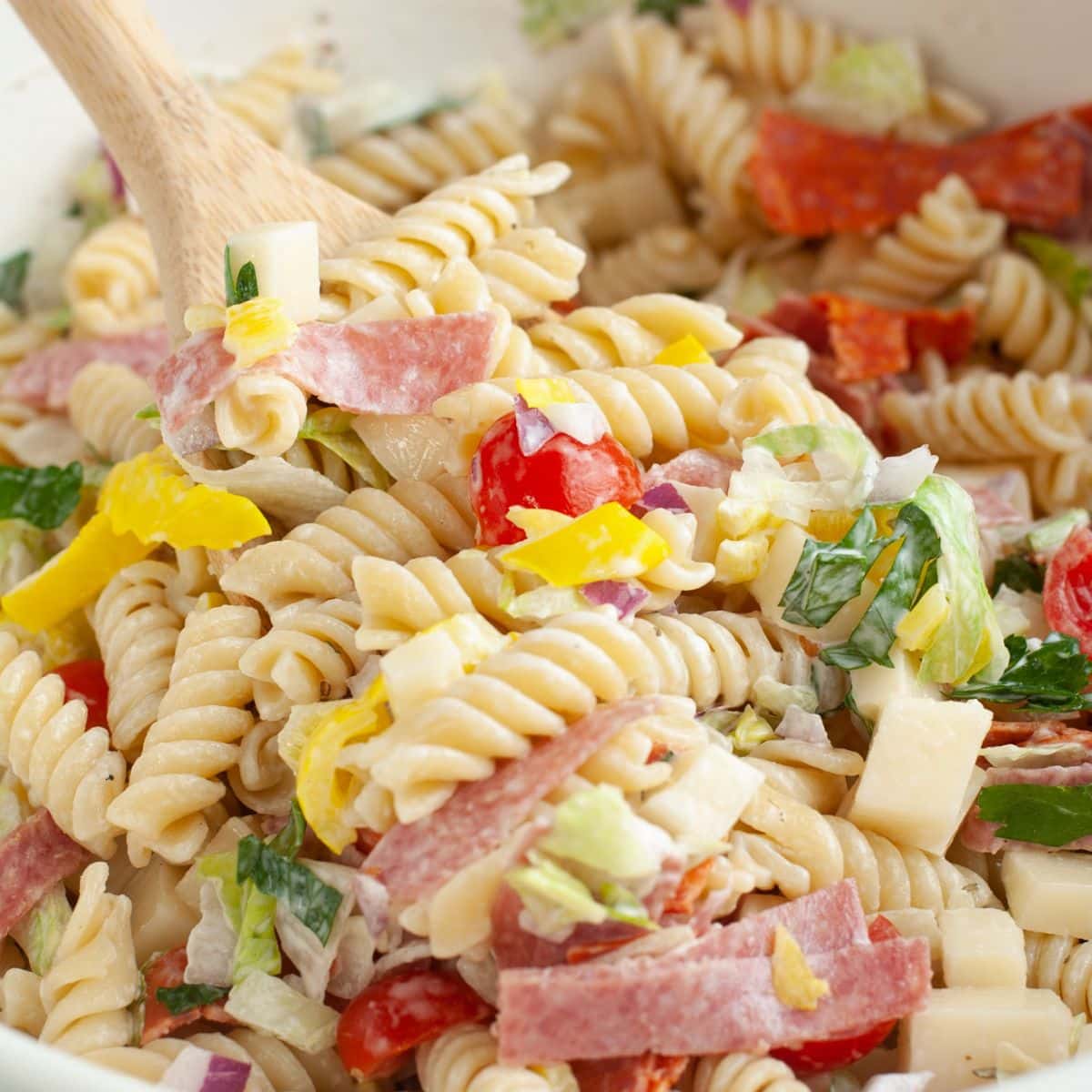 Italian sub pasta salad with a wooden spoon. 