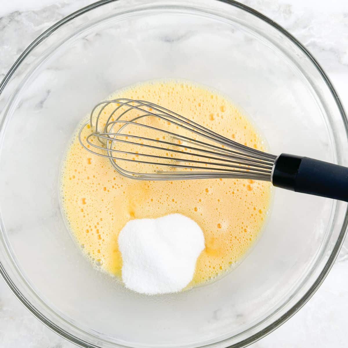 Bowl with beaten eggs, sugar, and a whisk.