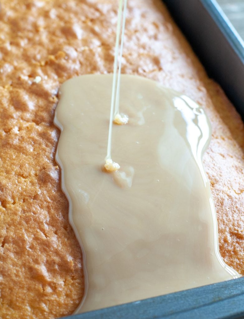 Mixture of caramel and condensed milk being poured on cake.
