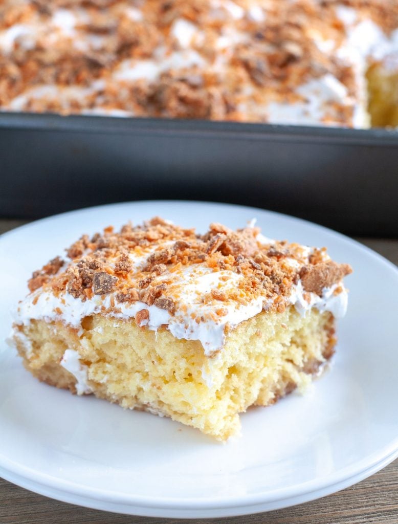 A piece of butterfinger poke cake on a white plate.