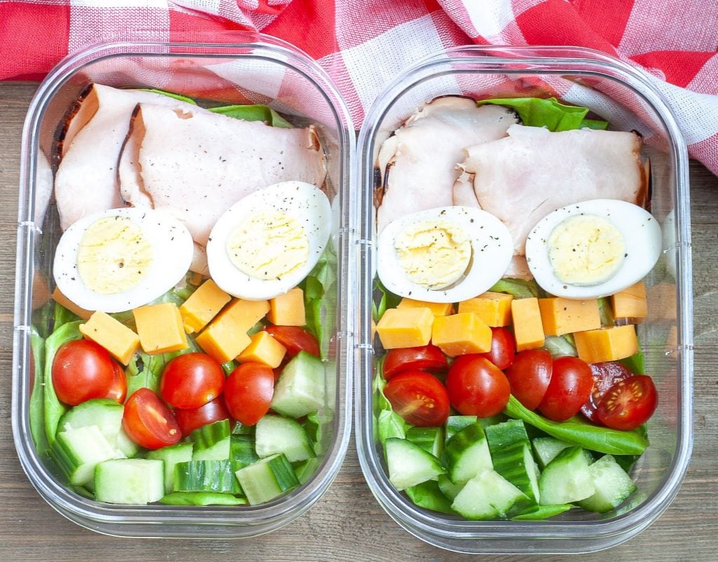 2 containers with turkey, hard boiled eggs, cheese, tomatoes and cucumber.