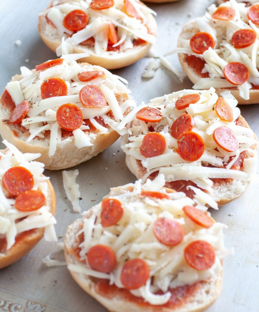 Unbaked pizza bagels on a sheet pan