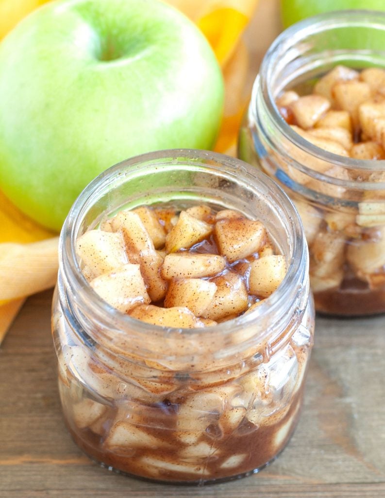 Apple pie filling in 2 small jars with apple in background