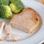 Pork chop on a plate with broccoli.