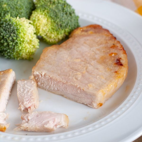 Pork chop on a plate with broccoli.