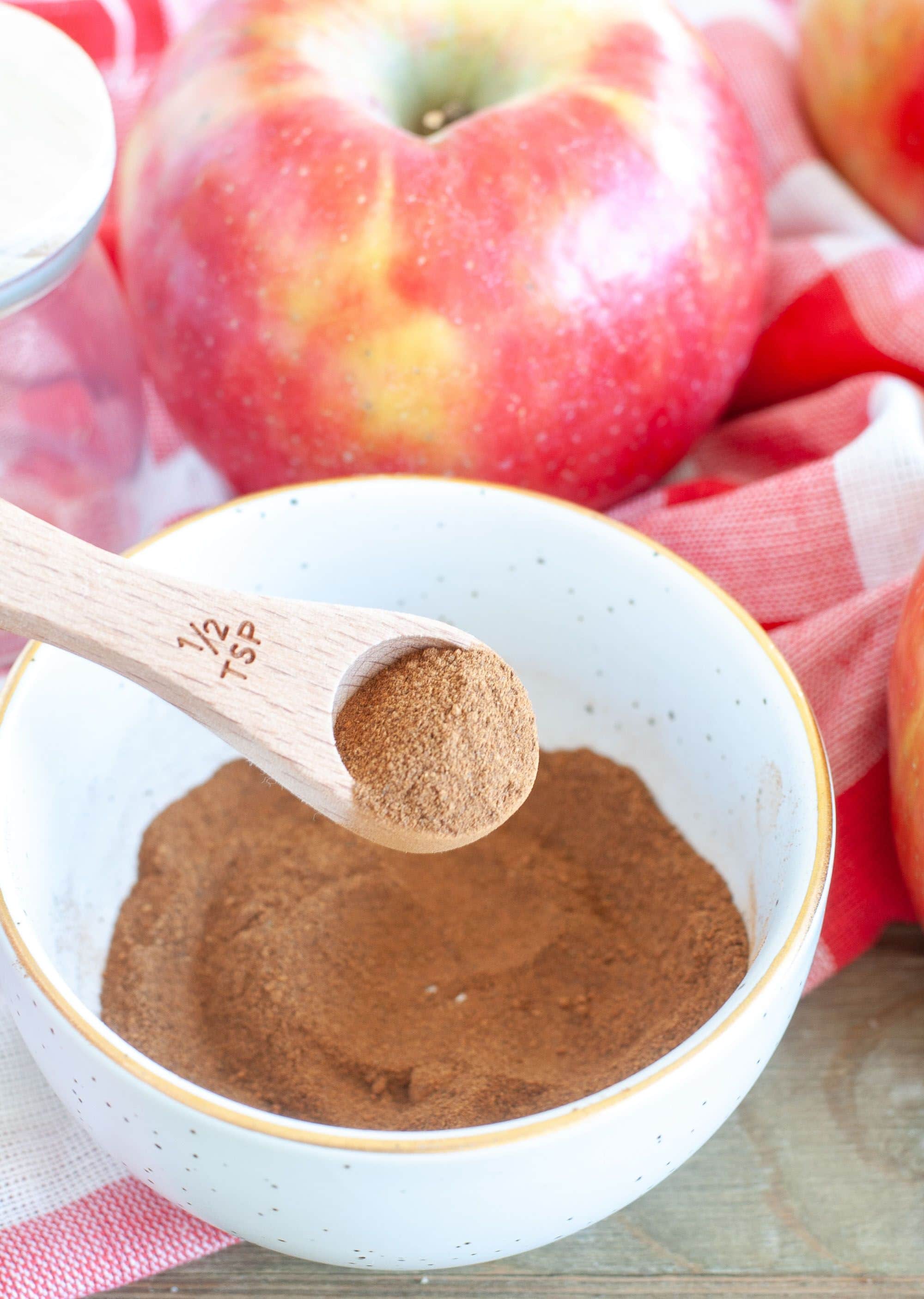 Bowl with aromatic apple pie spices and a wooden spoon, ready for baking.