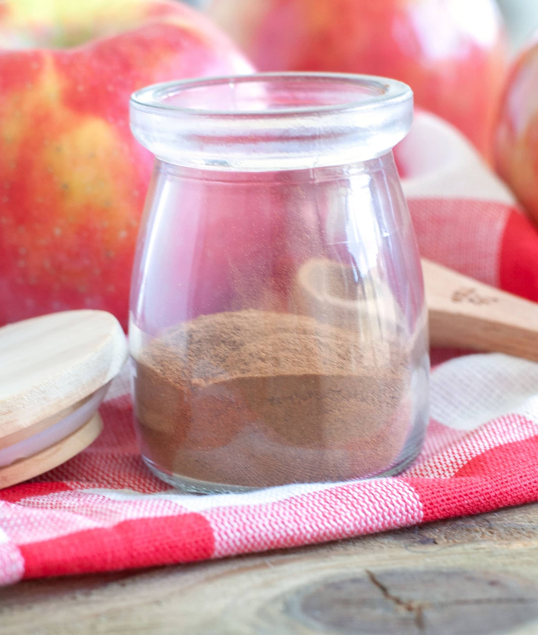 Apple Pie Spice A charming jar of homemade apple pie spice resting on a vibrant red napkin, symbolizing warmth and home.