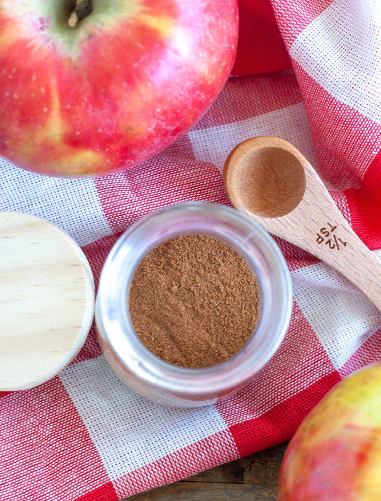 Apple Pie Spice in a jar and an apple and teaspoon