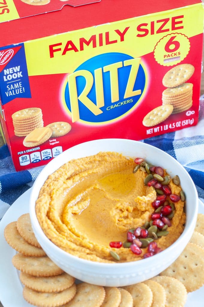 Bowl of pumpkin hummus with box crackers