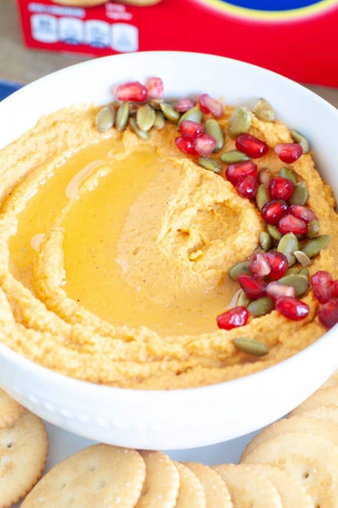 A bowl of pumpkin hummus with roasted pumpkin seeds and pomegranate seeds