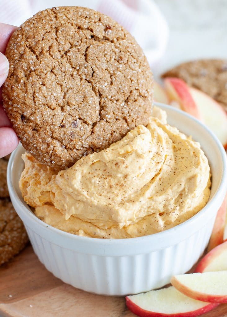 Ginger cookie being dipped in pumpkin dip